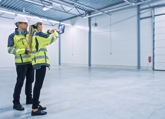 Modern Factory Two Engineers Use Digital Tablet Computer with Augmented Reality Software Visualizing of Manufacturing Plant Room Mapping