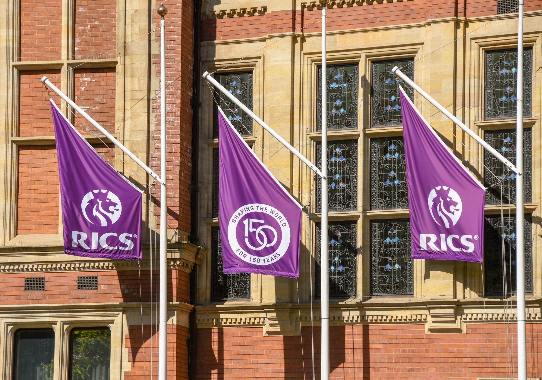 Banners on a building with the logo of the Royal Institute of Chartered Surveyors, the common abbreviation for which is RICS 