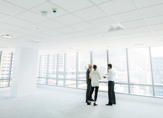 Wide angle shot of real estate agent with potential clients inside an empty office space  Estate broker showing new office space to business people 