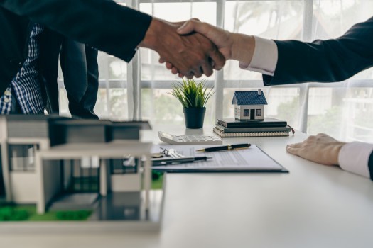 A home agent shakes hands with a customer after signing a contract to buy a home or rent it in the real estate agent's office 