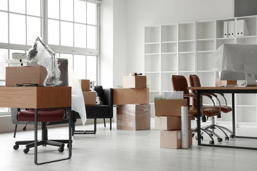 Workplaces with cardboard boxes in office on moving day